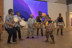 Group of people, some are African drumming, others are dancing