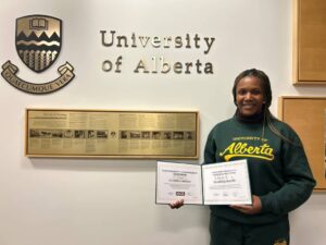 Scholar wearing UofA hoodie, holding her certificates